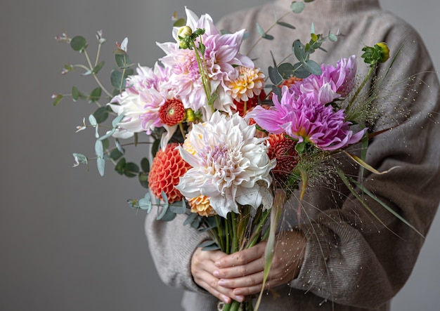 女性の手に菊と明るいお祝いの花束のクローズアップ。