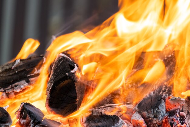 Close up of brightly burning wooden logs with yellow hot flames of fire at night.