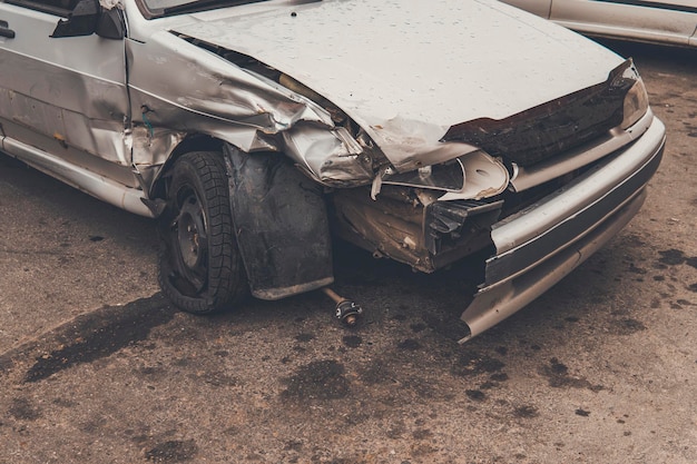 Foto un primo piano di un'auto rotta dopo un incidente stradale in un tempo nuvoloso gravi danni di un paraurti a