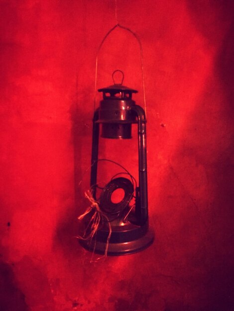 Photo close-up of broken lantern hanging by red wall