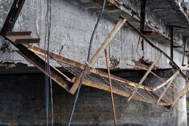 Foto primo piano di una passerella di metallo rotta su un vecchio ponte in cemento armato.