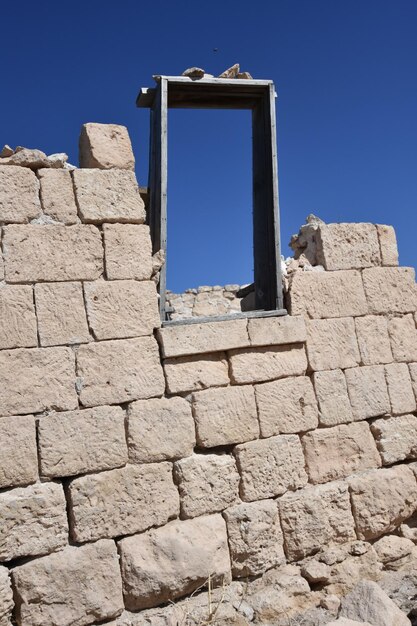 Photo close-up of broken stone wall against blue sky