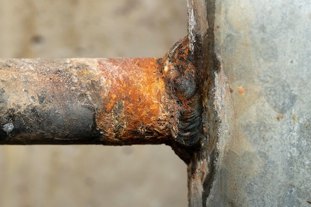 Photo close up of a broken weld at the welding site of two water pipes with water leakage and rust