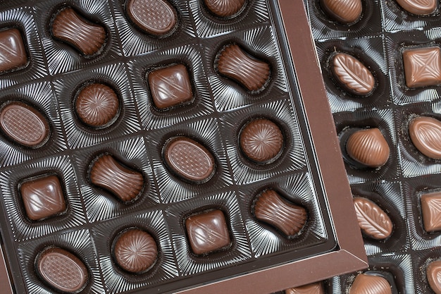 Close up brown chocolate candy background. Assortment of chocolate candies sweets in the box