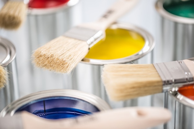 Close-up brushes lying on multicolored paint cans.