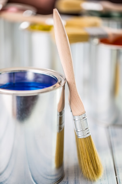 Close-up brushes lying on multicolored paint cans.