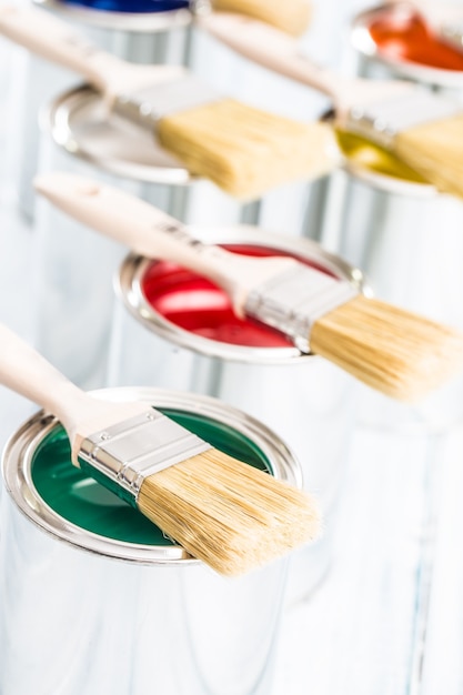 Close-up brushes lying on multicolored paint cans.