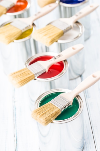 Close-up brushes lying on multicolored paint cans.