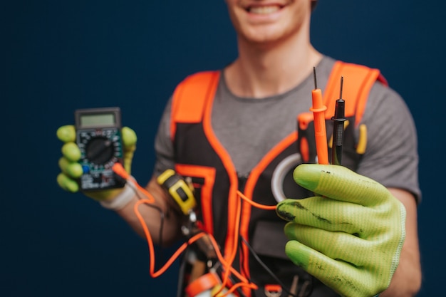 Photo close up builder is holding digital multimetert in gloves