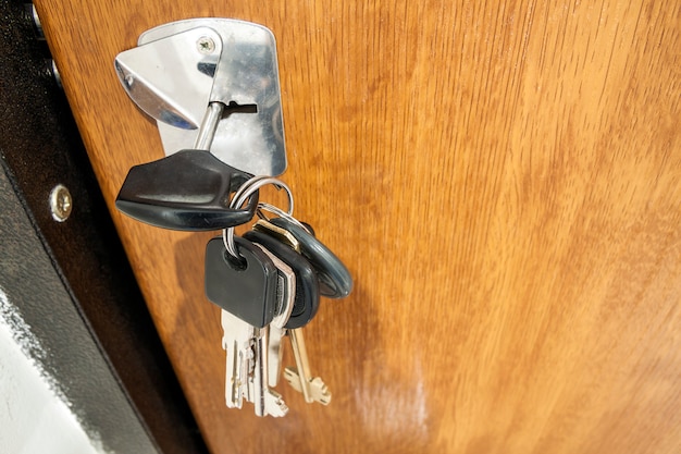 Close-up of bundle of different keys in key hole in wooden texture door.