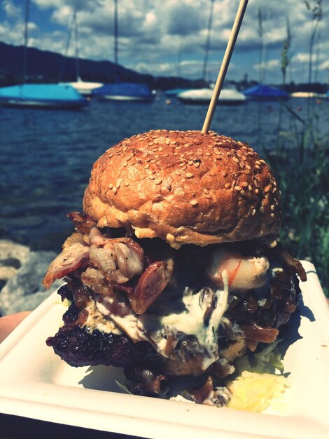 Photo close-up of burger in plate against sea