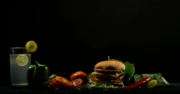 Photo close-up of burger and vegetables against black background