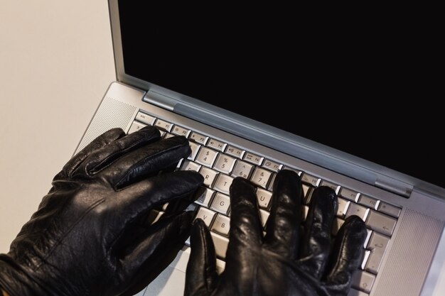 Close up of burglar hacking a laptop 