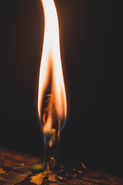 Photo close-up of burning candle in darkroom