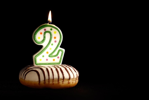 Photo close-up of burning candle on donut against black background