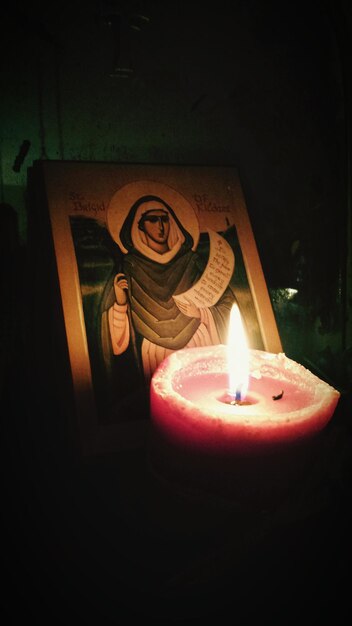 Photo close-up of burning candle in front of icon