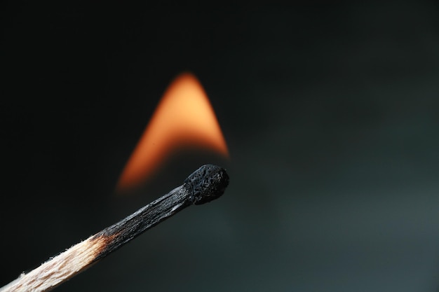 Foto close-up di un fiammifero in fiamme su sfondo nero