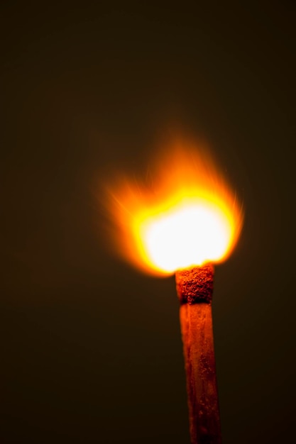 Foto close-up di un fiammifero in fiamme su uno sfondo nero