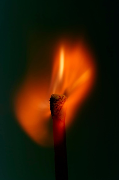 Foto close-up di un fiammifero in fiamme su uno sfondo blu