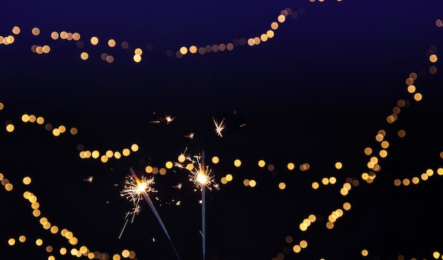 Close up of burning sparkler with bokeh lights