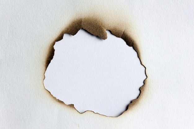 Photo close up burnt edges hole on white paper