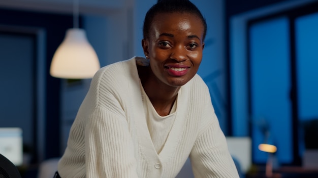 Close up of business african woman smiling at camera after typing on laptop