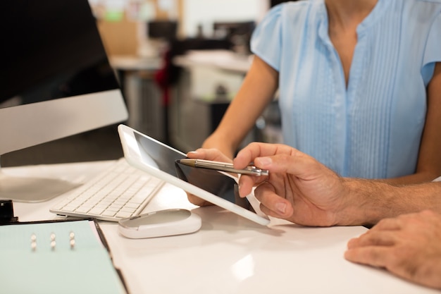 Close up of business colleagues discussing on digital tablet