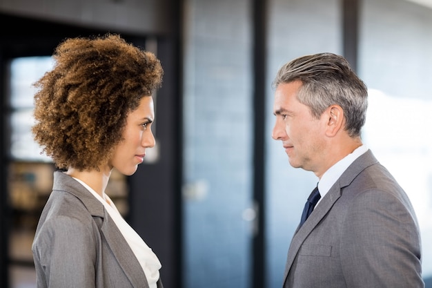 Primo piano dell'uomo di affari e della donna di affari che stanno faccia a faccia in ufficio