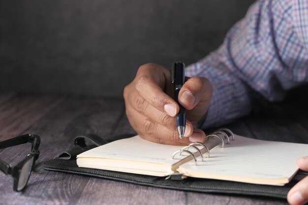 Photo close-up of business man hands writing on notepad