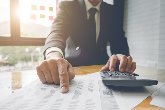 Close-up Business man met behulp van een calculator en wijzen op document data voor de berekening, belasting, boekhouding, Accountant concept.