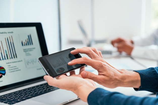 Close up. business man using his smartphone to analyze a financial chart . people and technology.