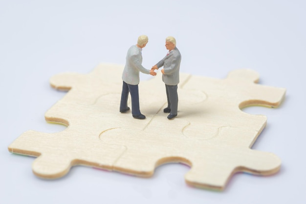 Close-up of business people figurines on jigsaw puzzle against white background