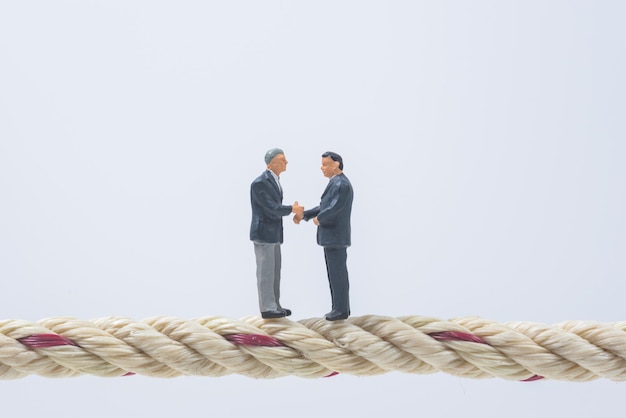 Photo close-up of business people figurines on rope against white background