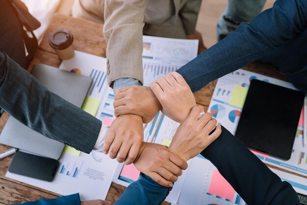 Close up business people holding each others wrists join hands together support and unity team strength and power colleagues involved in team building activity