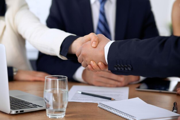 Close up of business people shaking hands at meeting or negotiation in the office. Partners are satisfied because signing contract.