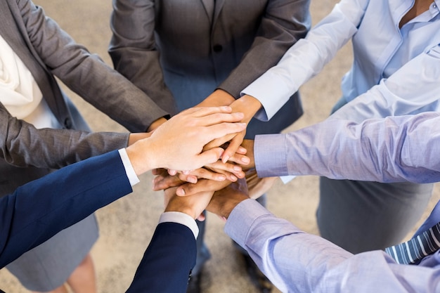 Close-up of business people stacking hands in meeting at office