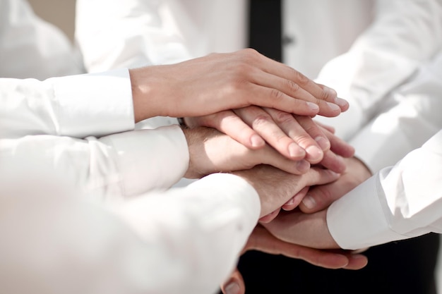 Chiuda in su uomini d'affari con una pila di mani il concetto di lavoro di squadra