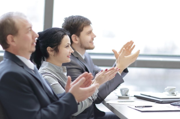 Close-up business team applaudisseren voor de spreker die op de werkplek zit