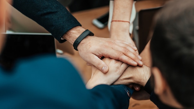 Close up business team folding their palms over the desk