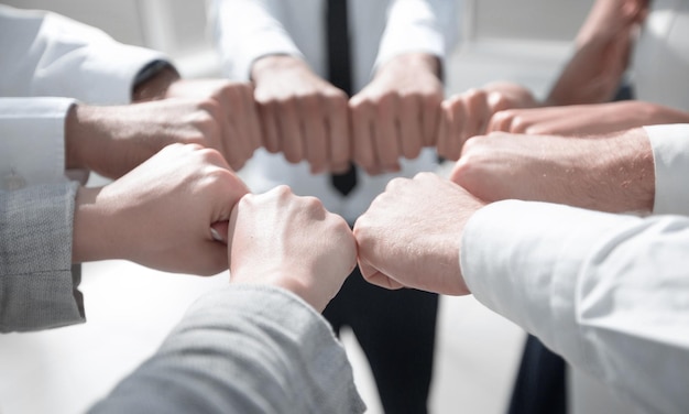 Close up business team forming a circle out of their fists