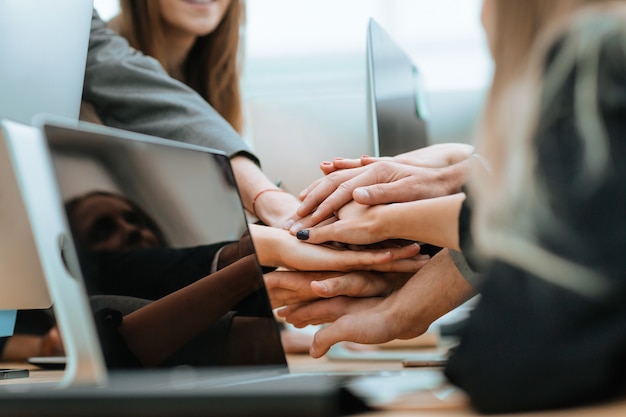 Close up business team joining their hands over the desk