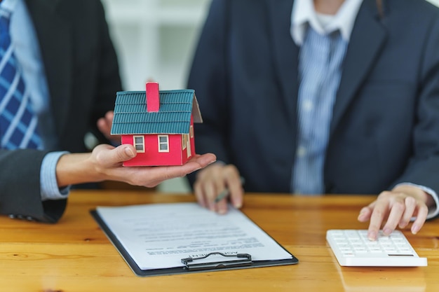 Close up Business woman or agent checking agreement contract before giving house for buying house Bank manager and real estate concept