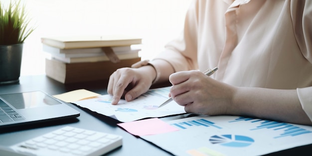 Close up business woman checking a graph on a wooden desk in the office