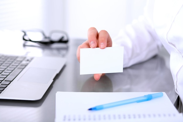 Photo close-up of business woman giving a visit card.