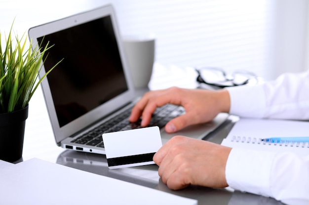 Close up of business woman hands using credit card and laptop computer