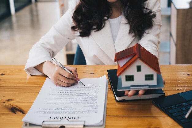 Close up of Business woman pointing and signing agreement for buying house Bank manager concept