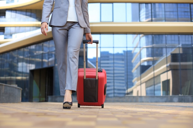 Close up of business woman pulling luggage while walking outdoors