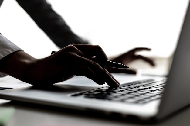 Close-up of business woman's hand silhouette typing on laptop keyboard, she is typing on a laptop keyboard, she uses a messenger to chat with a partner. Concept of using technology in communication.