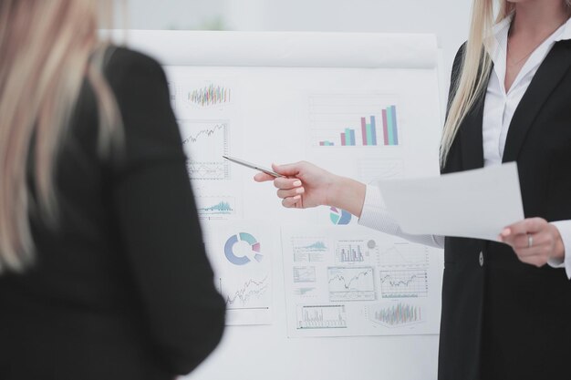 Photo close up business woman showing a pen on a flipchart with financial data