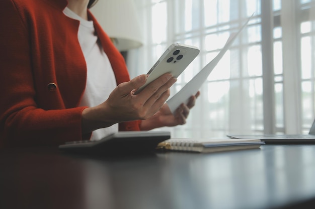 Close up Business woman using calculator and laptop for do math finance on wooden desk tax accounting statistics and analytical research concept